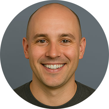 Smiling bald man in a grey shirt with a neutral background.