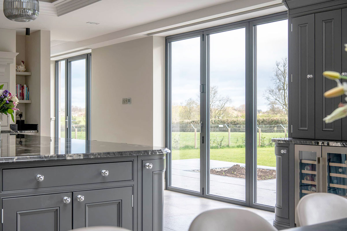 Aluminium bi-fold doors in a modern kitchen overlooking a garden.