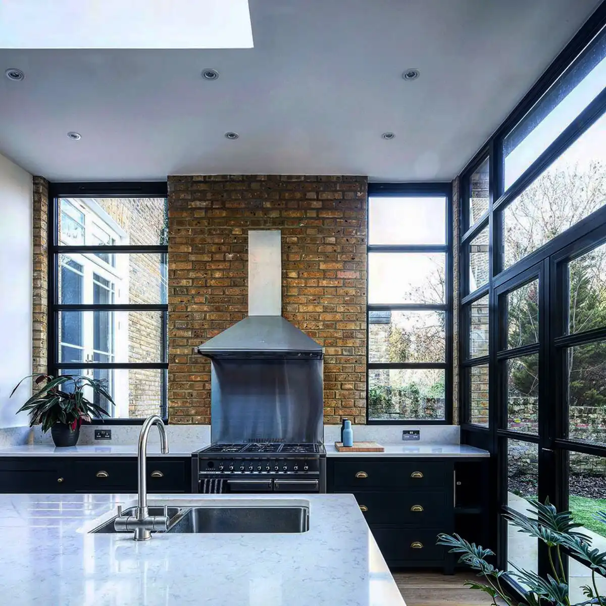 Contemporary kitchen with black heritage aluminium windows framing exposed brick and sleek modern finishes.
