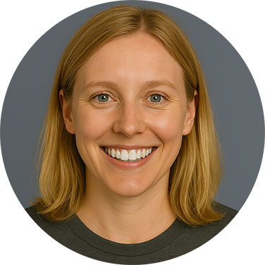 Smiling blonde woman in a dark shirt with a neutral grey background.