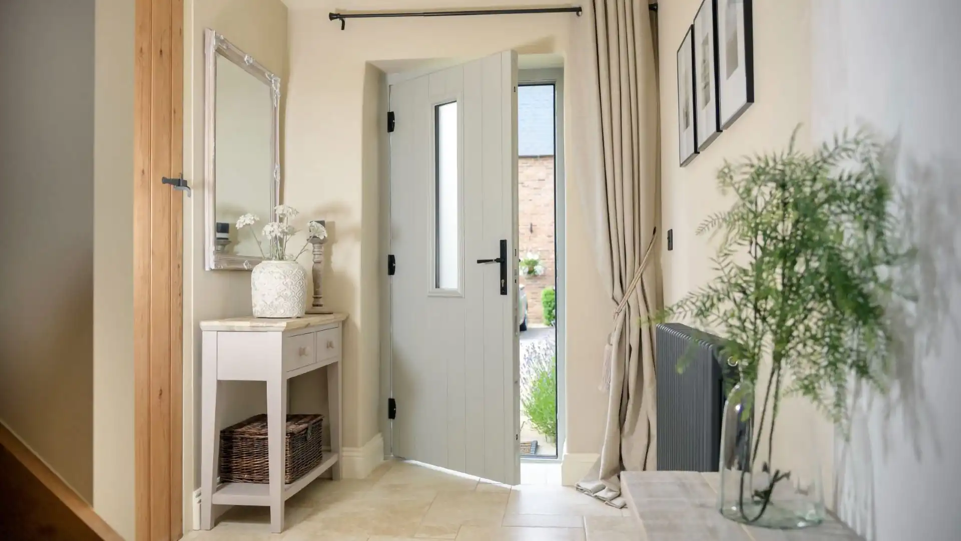 Light grey composite front door with vertical glass panel opening into a cosy, well-decorated hallway.