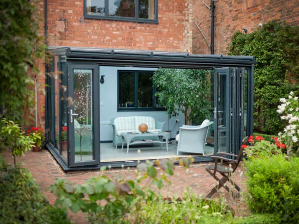 Modern black-framed lean-to conservatory with full glass walls and garden patio