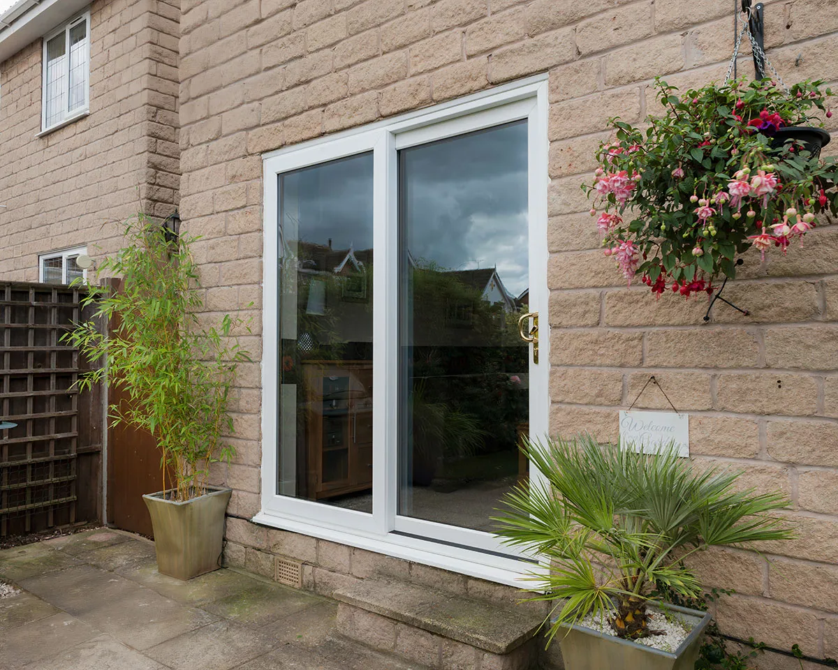 White uPVC sliding patio doors leading to a garden area with potted plants.