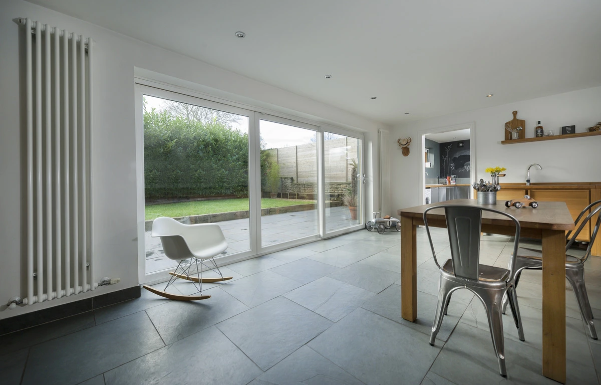 White uPVC sliding patio door in a bright kitchen-diner, opening onto a garden with slate flooring.