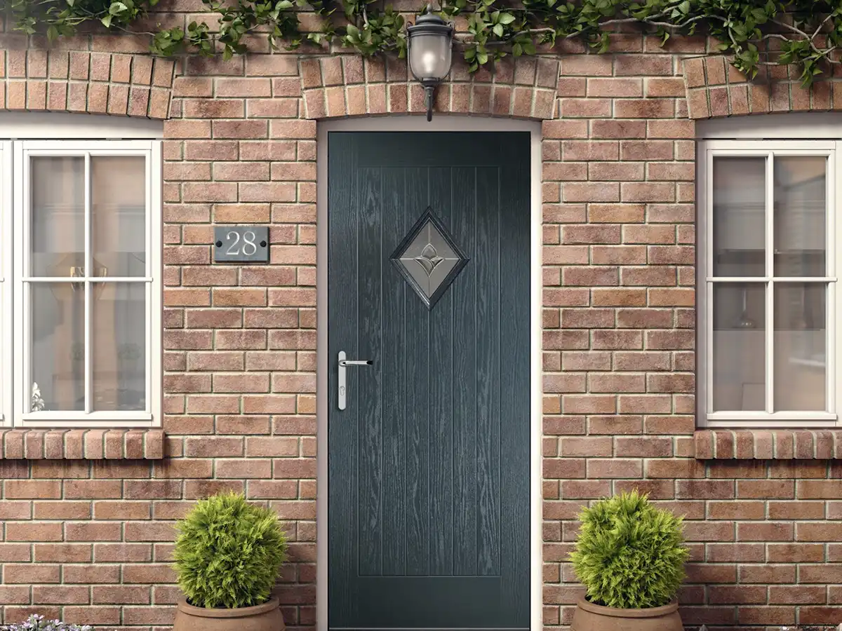 Black composite front door with diamond glass panel on a red brick house.