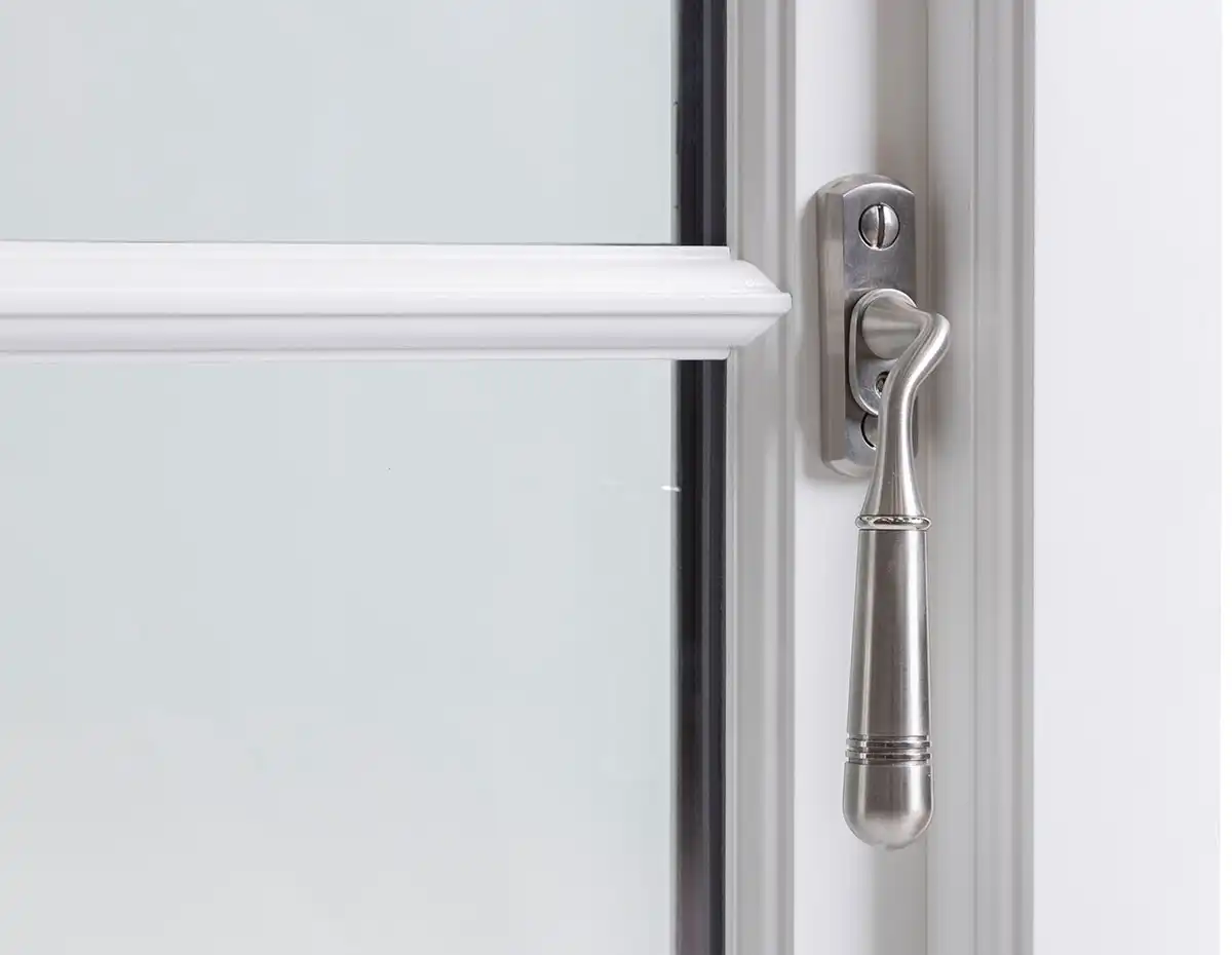 Close-up of a brushed metal handle on a white wooden casement window for secure and stylish operation